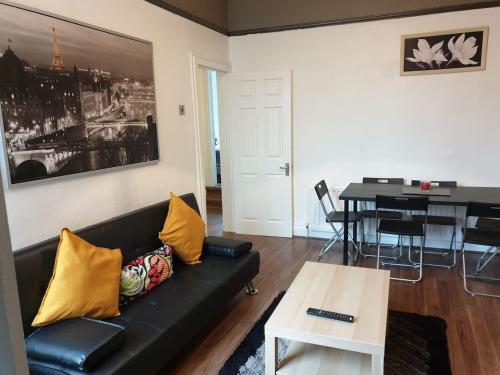 a living room with a black couch and a table at South Shield's Hidden Gem Garnet 3 Bedroom Apartme in South Shields
