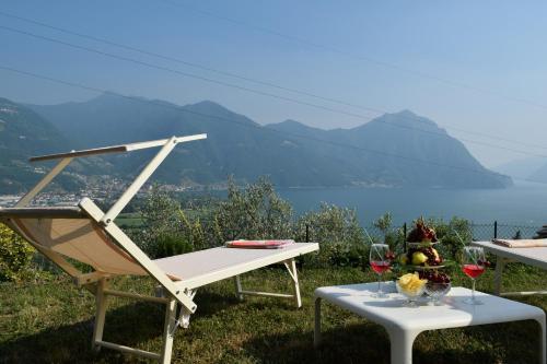 una mesa con dos copas de vino y una silla en Villa Domus Bianca Mountain Lake Iseo Hospitality en Costa Volpino