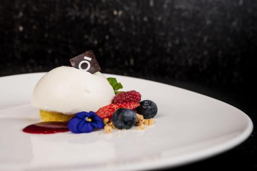 a dessert with berries on a white plate at Monroc Hotel in Commezzadura