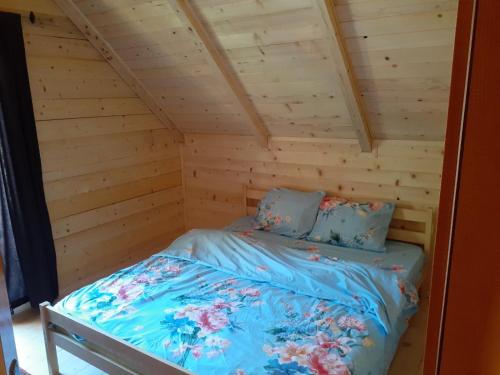 Bett in einem Blockhaus mit blauer Bettwäsche und Kissen in der Unterkunft Villas Meti Rugove in Peja