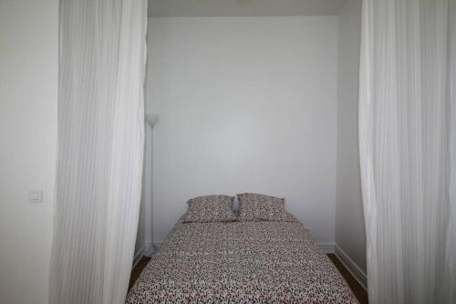 a bed in a bedroom with white walls at Quartier Historique du Château bel appt meublé in Pau