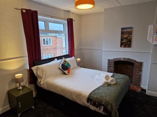 a bedroom with a bed with a fireplace and a window at Grange Villa Amethyst 3 Bed House in Chester-le-Street