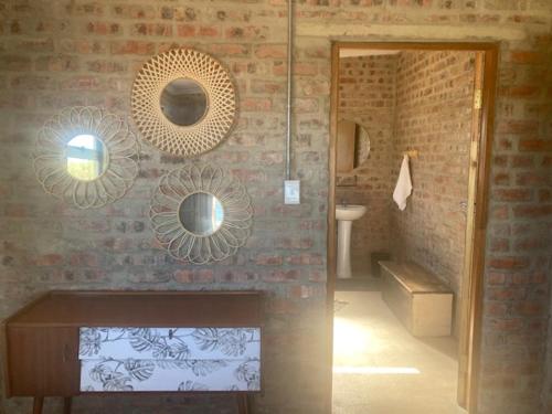 a bathroom with a sink and a brick wall at De Poort Cottage in Bredasdorp