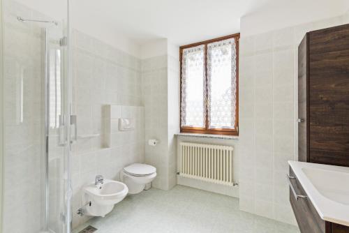 a white bathroom with a toilet and a sink at Casa Elena in Ledro