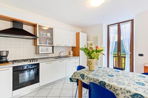 a kitchen with white cabinets and a table with blue chairs at Casa Elena in Ledro
