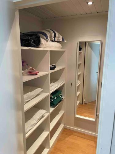 a walk in closet with white shelves and a mirror at Trevligt hus & Sjöbod i mysiga Mollösund Tången in Mollösund