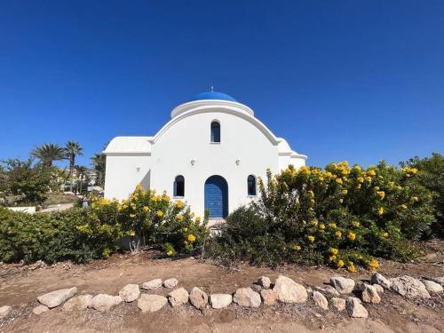 a small white church with a blue dome at Apartament na Cyprze in Peyia