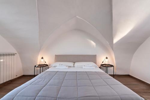 ein großes Bett in einem weißen Zimmer mit zwei Lampen in der Unterkunft Doberdò Exclusive House & SPA Bath - SIT Apartment in Carmiano