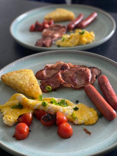 two plates of food with sausage and other foods at Pearl's Homestay Matale in Matale