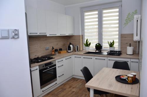 kuchnia z białymi szafkami i drewnianym stołem w obiekcie Apartament Gustav w mieście Zawiercie