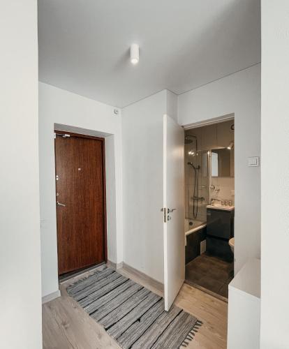 a white room with a door and a bathroom at Marijampole Apartment with FREE Parking in Marijampolė