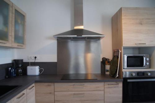 une cuisine avec une cuisinière et un micro-ondes dans l'établissement Maison classée meublé 3 étoiles, proche mer., à Sainte-Maxime