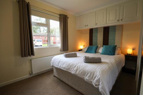 a bedroom with a large white bed with blue pillows at Charming Hazel Lodge - Relaxing Devon Getaway in Chudleigh