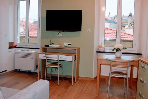 a living room with a desk with a tv and two chairs at Studio DolceCasa Menton in Menton