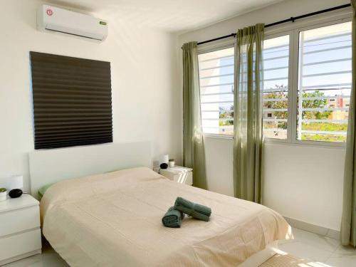 ein Schlafzimmer mit einem Bett mit einem Paar Schuhe darauf in der Unterkunft Villa Ana Luisa - Pool, AC, 3min to Beach, Modern 3BD/3.5BA in La Romana