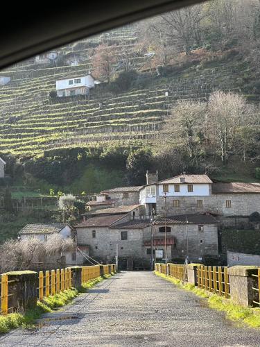 a dirt road with a village on a hill at Amodiño do Camiño in Belesar