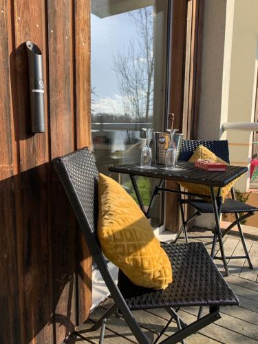 une chaise avec un oreiller jaune sur la terrasse dans l'établissement Hôtel L'ile Du Saussay, à Itteville