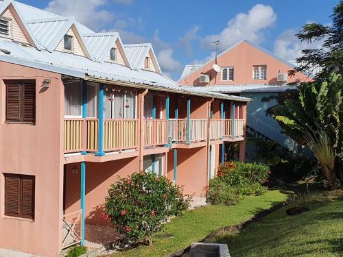 un edificio rosa con balcones blancos y patio en appartement KER-EOL Sainte-Anne avec piscine en Sainte-Anne