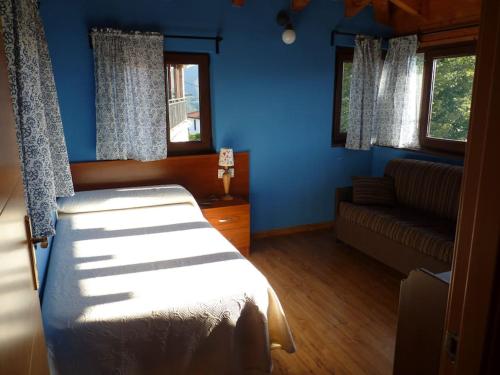1 dormitorio con paredes azules, 1 cama y 1 sofá en Vivienda Vacacional La Cantera en Cangas de Onís