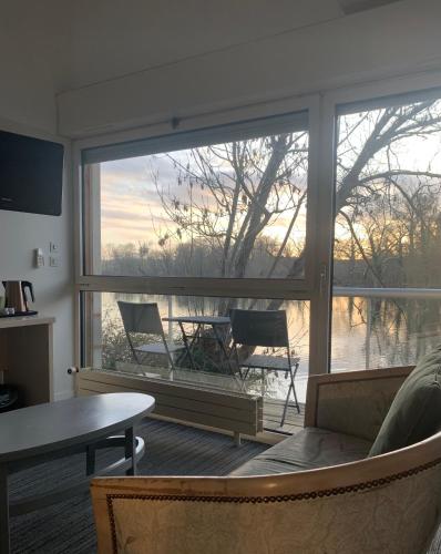a living room with a large window with a view of a tree at Hôtel L'ile Du Saussay in Itteville