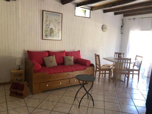 un salon avec un canapé rouge et une table dans l'établissement Gîte insolite - Domaine Shanti Lande, à Ménesplet