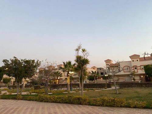 a building with palm trees in front of a park at Heliopolis Residence Shrouk city Cairo in Madīnat ash Shurūq