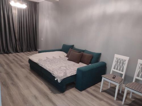 ein Schlafzimmer mit einem Bett, einem Sofa und 2 Stühlen in der Unterkunft Светлая квартира в центре Бишкека! in Bischkek