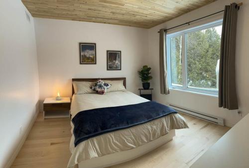 um quarto com uma cama e uma grande janela em Chalet Bellevue (Mont-Comi) em Saint-Gabriel
