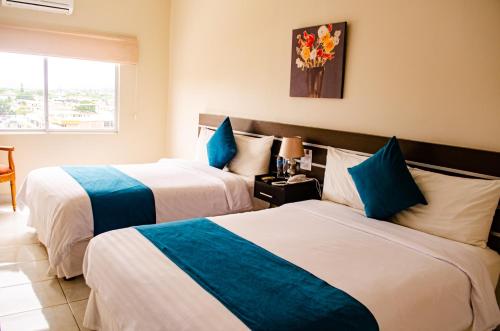 a hotel room with two beds and a vase of flowers at Hotel Ceibo Dorado in Portoviejo