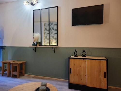 a room with a table and a television on the wall at Le nid vert in Eaux-Bonnes