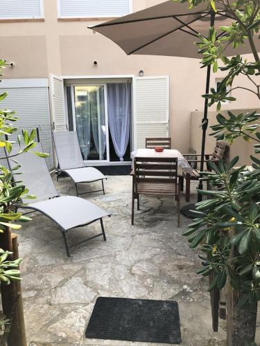 a patio with a table and chairs and an umbrella at Studio Rez de jardin dans résidence privée près de la plage in Calvi