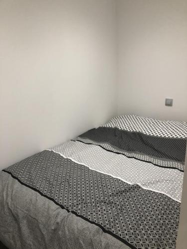a bed with a gray comforter in a bedroom at Studio Rez de jardin dans résidence privée près de la plage in Calvi