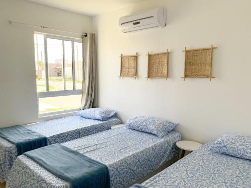 a room with three beds and a window at Casa Iva - Condomínio Fechado in Marechal Deodoro