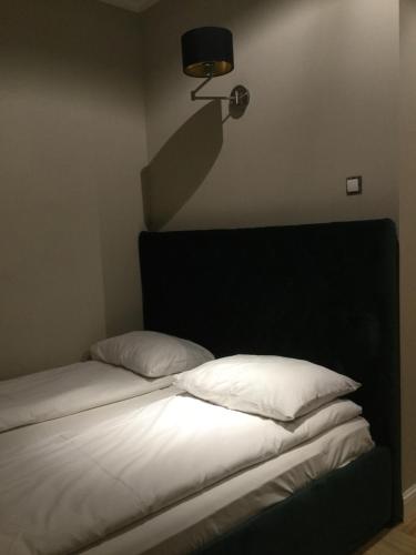 a bed with white sheets and a lamp on the wall at President Apartments by WarsawResidence Group in Warsaw