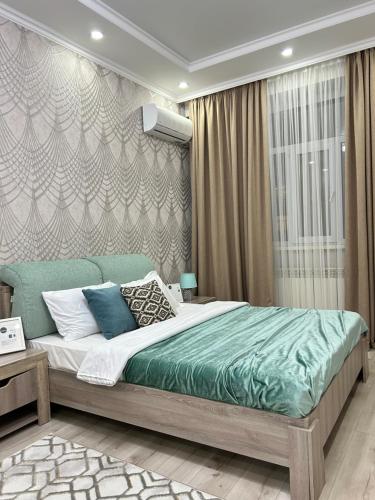 a bedroom with a large bed with a green blanket at Apartments GREEN PLAZA с видом на море in Aktau