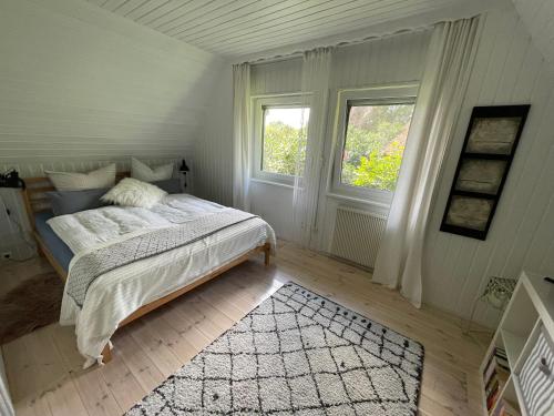 a bedroom with a bed and two windows and a rug at Tiny House Ostsee # Naturwerk in Pruchten