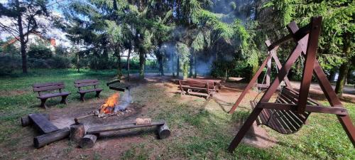 a fire pit in a park with benches and trees at Domek letniskowy na mazurach in Orzechowo