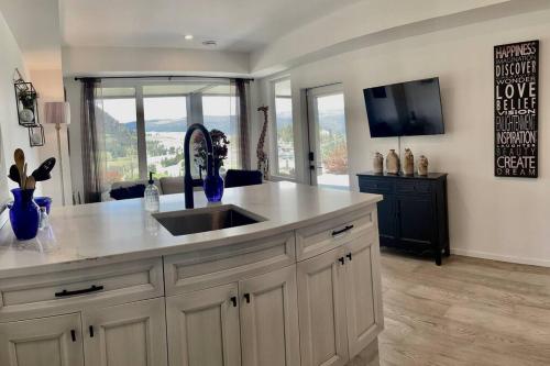 a kitchen with a sink and a tv in a room at Black Mountain Amazing Home on Golf Course in Kelowna
