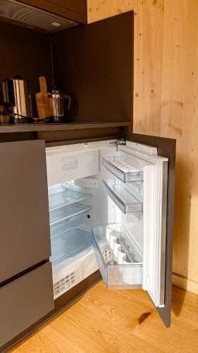 an empty refrigerator with its door open in a kitchen at Cabin Westerwald Sauna, 5G Internet, E-Ladesäule in Niederdreisbach