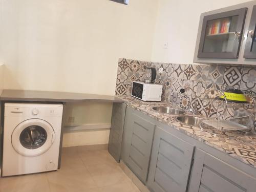 eine Küche mit einer Spüle und einer Waschmaschine in der Unterkunft Bel appartement au centre ville de calavi BENIN in Abomey-Calavi