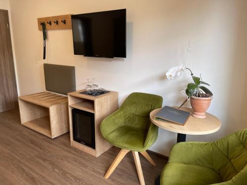 un soggiorno con sedia verde, tavolo e TV di Haus Schatzgarten a Traben-Trarbach