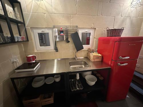 a kitchen with a red refrigerator and a sink at Ta Pinu Spa Suite - Luxury Heritage Living in Żebbuġ