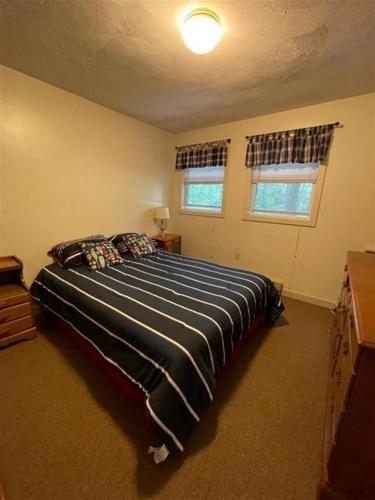 ein Schlafzimmer mit einem großen Bett mit einer blau gestreiften Decke in der Unterkunft BASS COVE 1 LIMIT 6 home in Casco