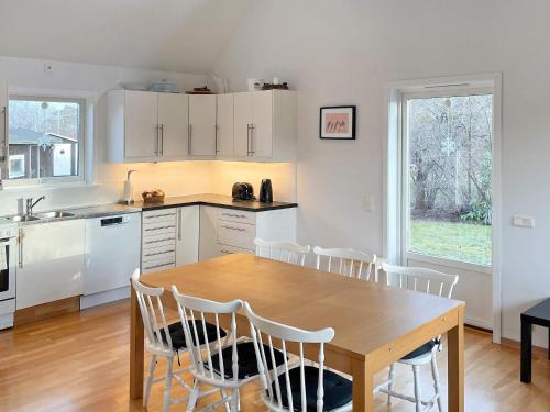 uma cozinha com uma mesa de madeira e armários brancos em Holiday home ROCKNEBY III em Rockneby