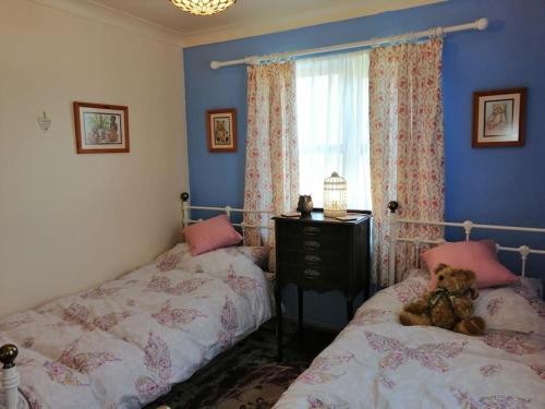 a bedroom with two beds and a teddy bear sitting on the bed at Lovely Stone Village cottage in Snowdonia in Waenfawr