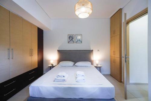1 dormitorio con 1 cama blanca grande y toallas. en Cozy Stay in Glyfada with WiFi, Garden, Parking, en Atenas