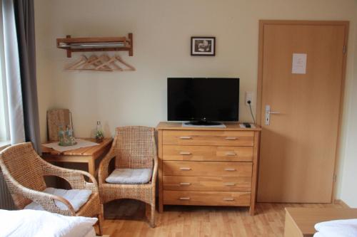 a living room with a television on a dresser with chairs at Restaurant Fischbeck´s in Großenkneten