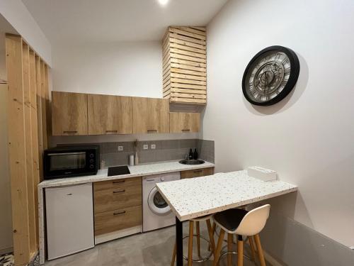 cocina con encimera y reloj en la pared en Studio cosy à 15 min de Bordeaux, en Saint-Sulpice-et-Cameyrac