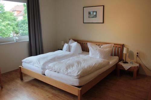 a bedroom with a bed with white sheets and a window at Restaurant Fischbeck´s in Großenkneten