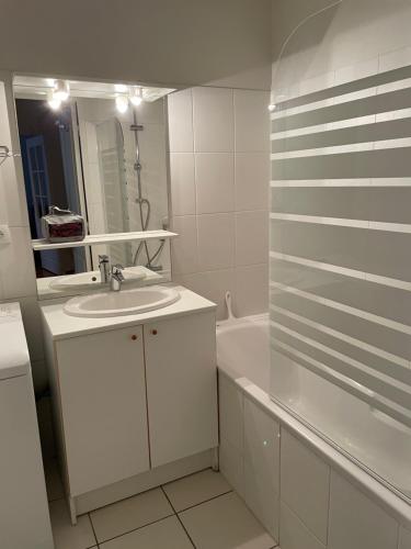 a white bathroom with a sink and a tub at Appartement moderne cœur des châteaux de la Loire - Parking in Blois
